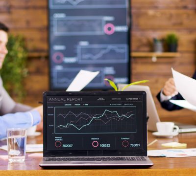 On the table laptop showing charts in the conference room. Business people having an important discussion.
